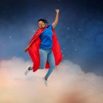Woman wearing a superhero cape jumping for joy