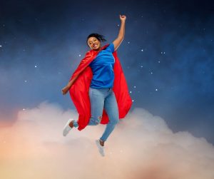 Woman in superhero cape jumping for joy