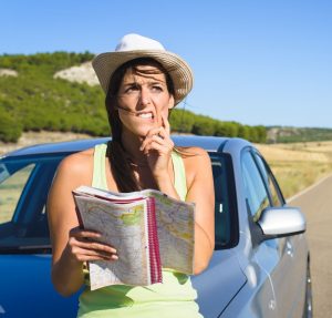 Woman who appears to be lost leaning on a car.