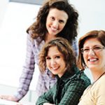 photo of three women sitting at a computer smiling